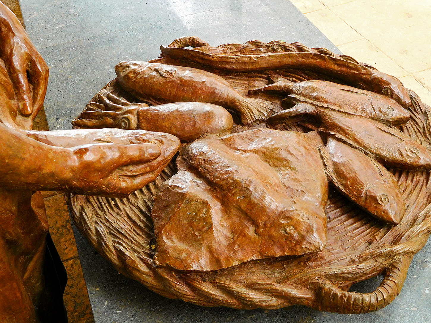 Primer plar de la panera, el peix i la ma de la peixatera, recent instal·lada